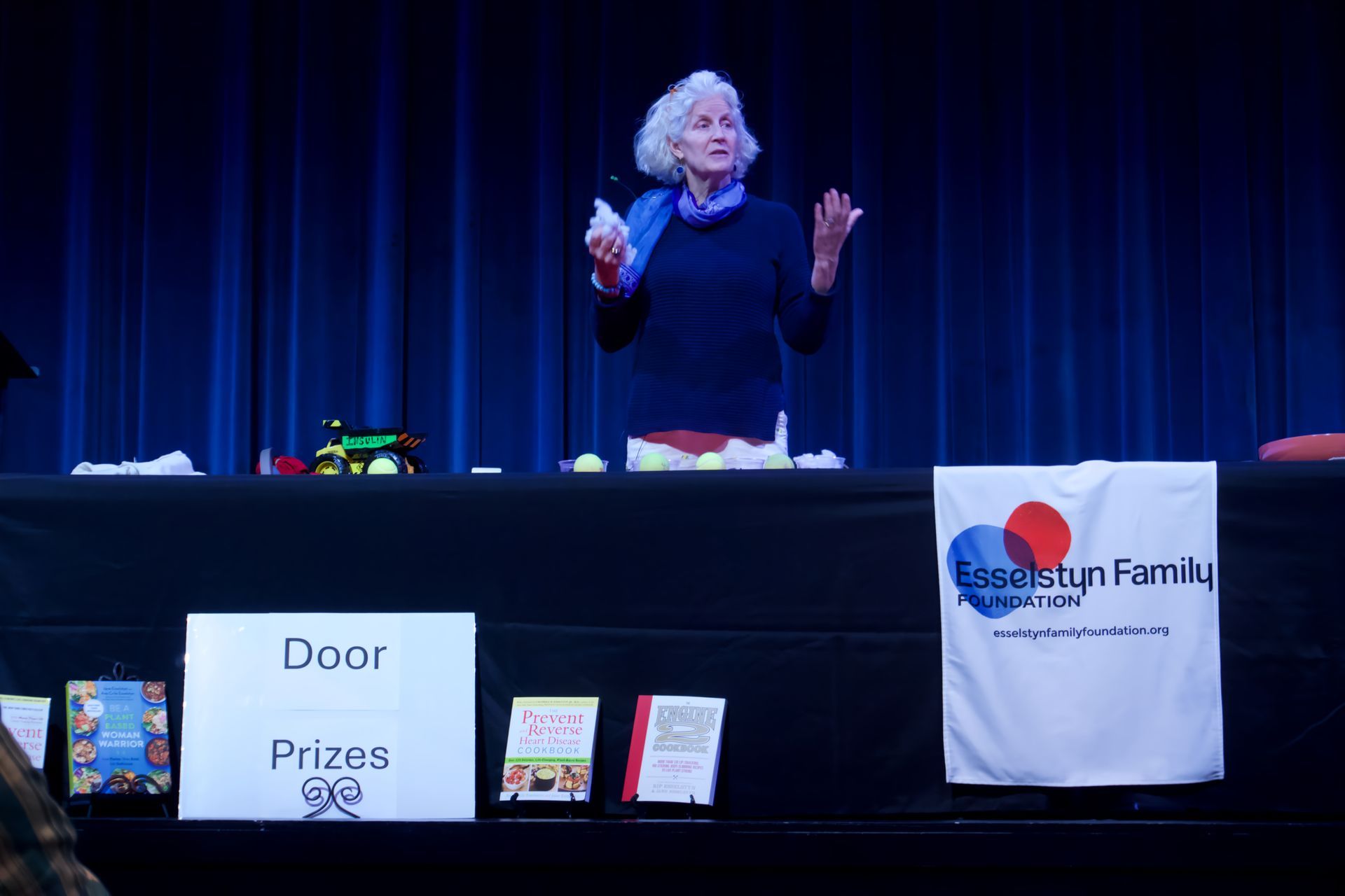 A woman stands behind a table with a sign that says door prizes