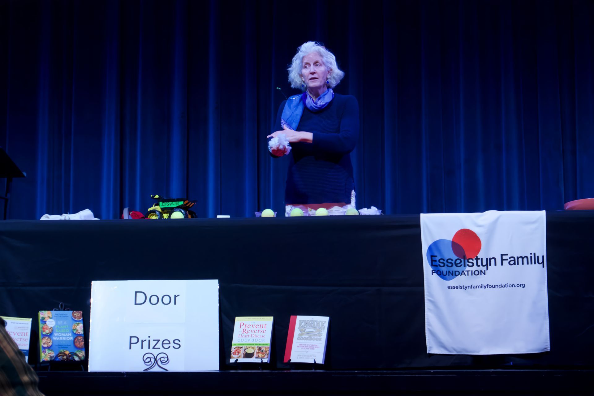 A woman is standing behind a table with a sign that says door prizes.