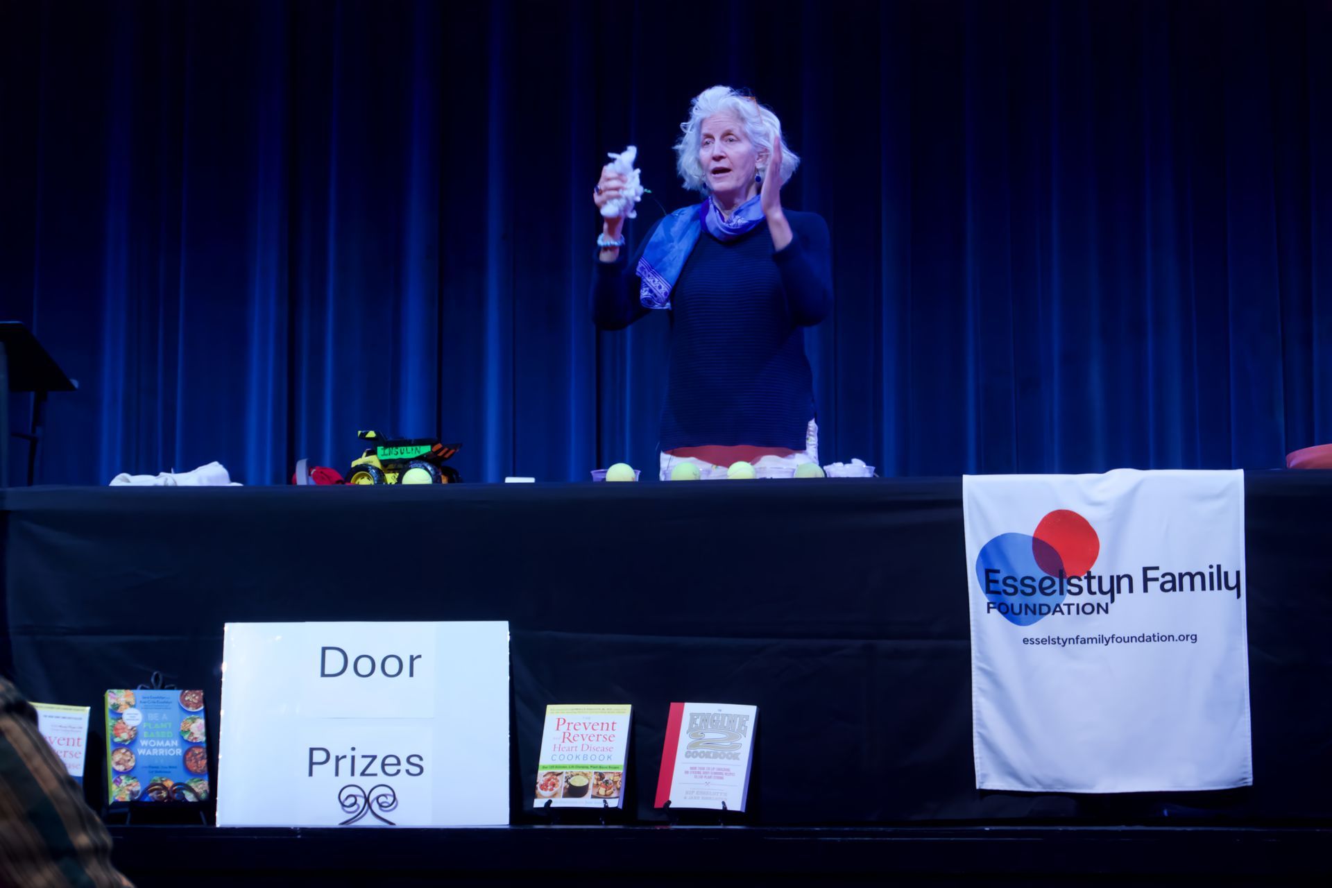 A woman stands behind a table with a sign that says door prizes