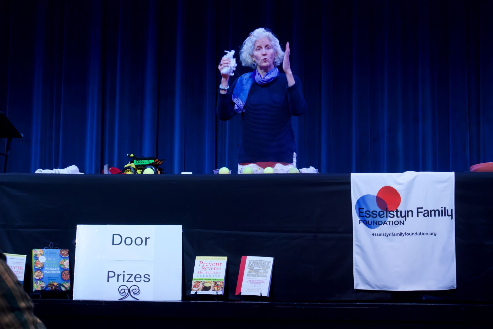 A woman stands behind a table with a sign that says door prizes