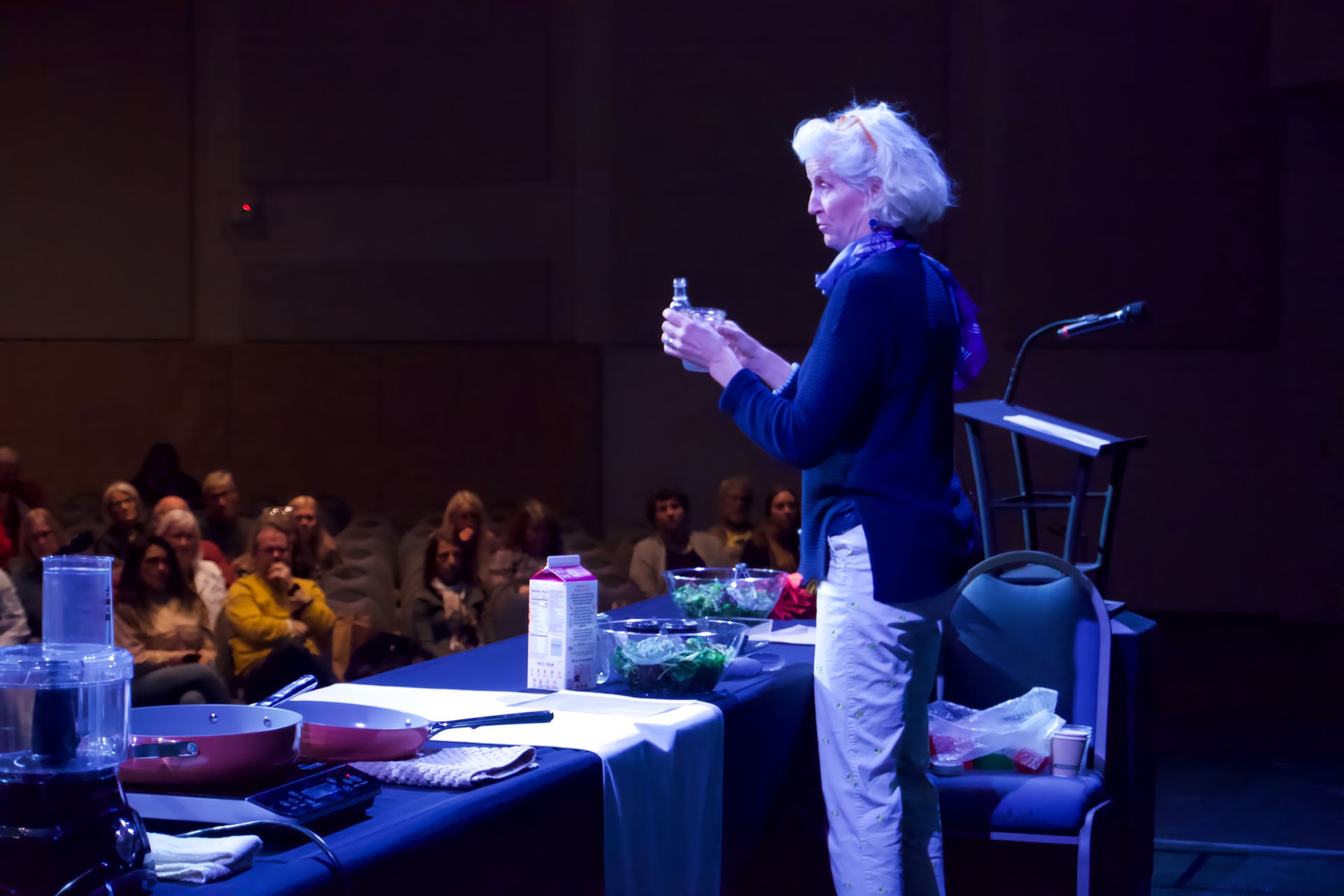 A woman is standing on a stage giving a presentation to a group of people.