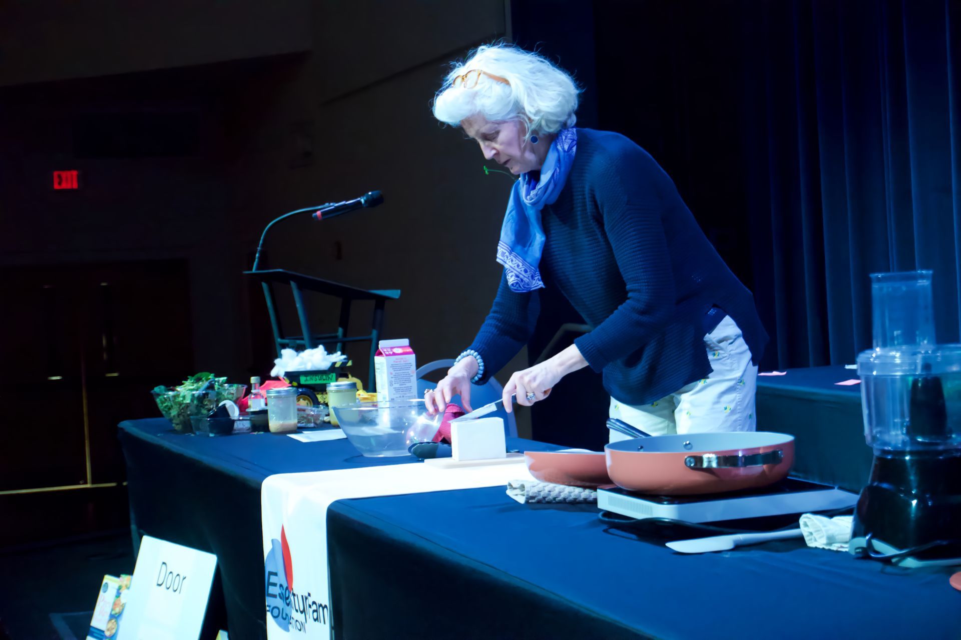A woman is preparing food on a table in front of a microphone