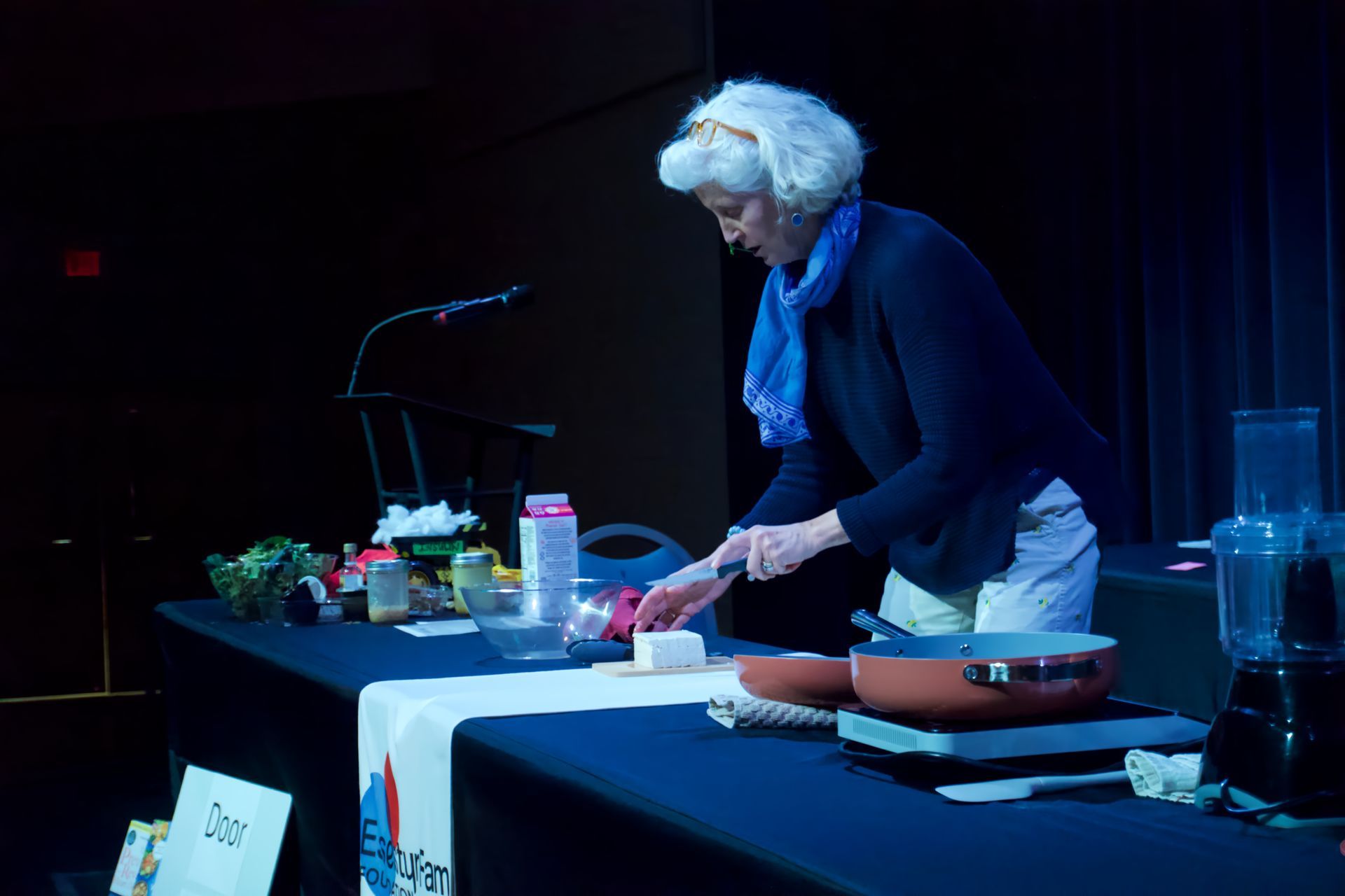 A woman is preparing food on a table in a dark room