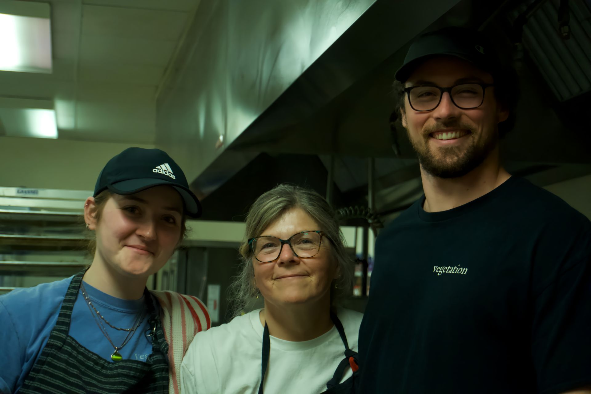 A man and two women are posing for a picture in a kitchen.