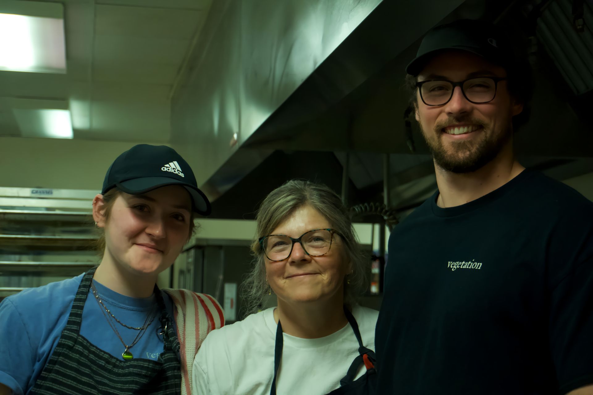 A man and two women are posing for a picture in a kitchen.