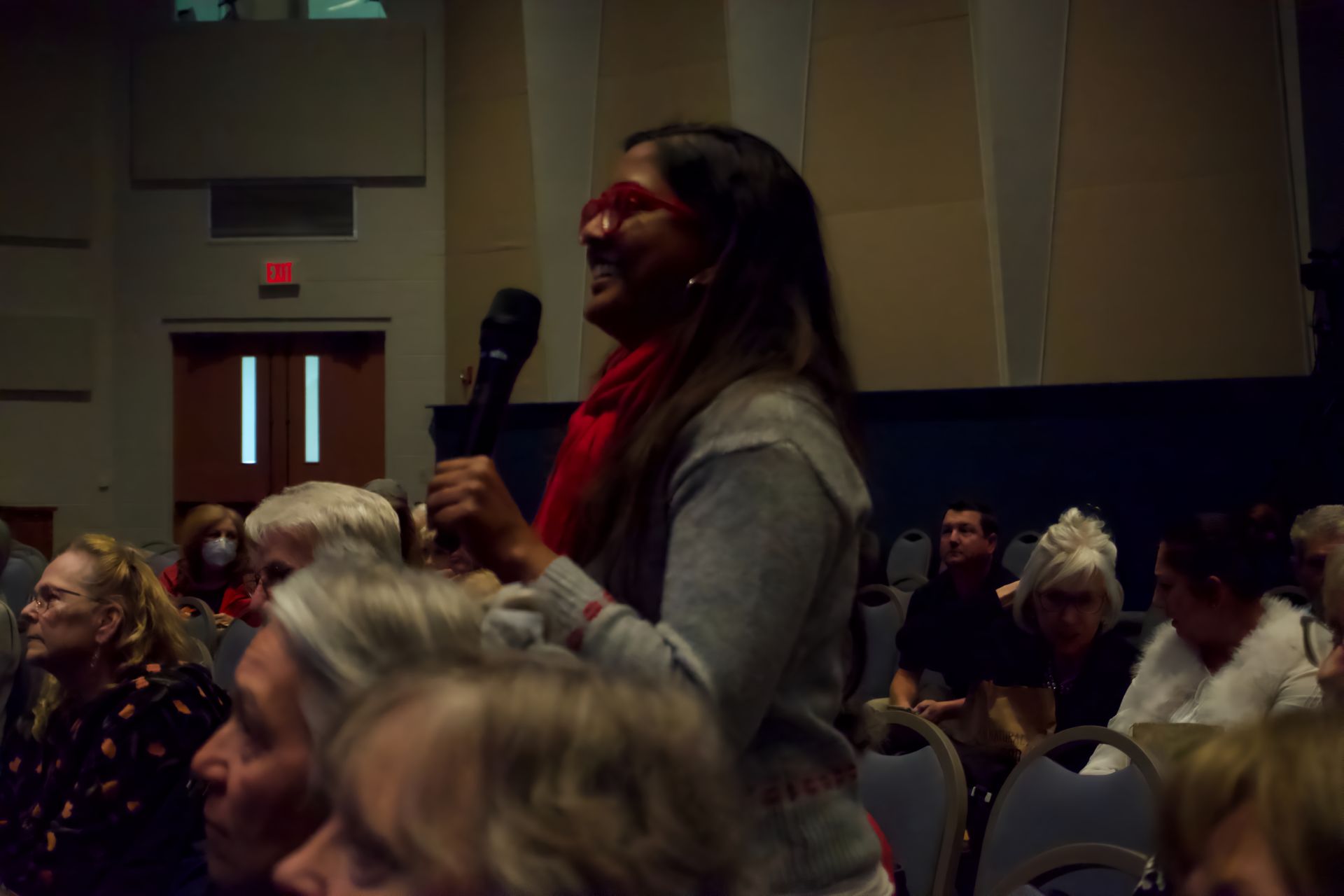 A woman is holding a microphone in front of a crowd of people.
