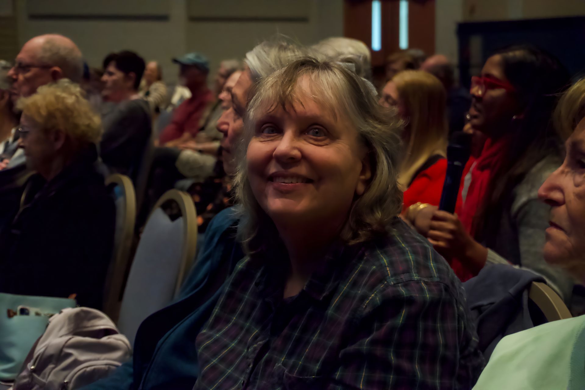 A woman is smiling while sitting in a crowd of people