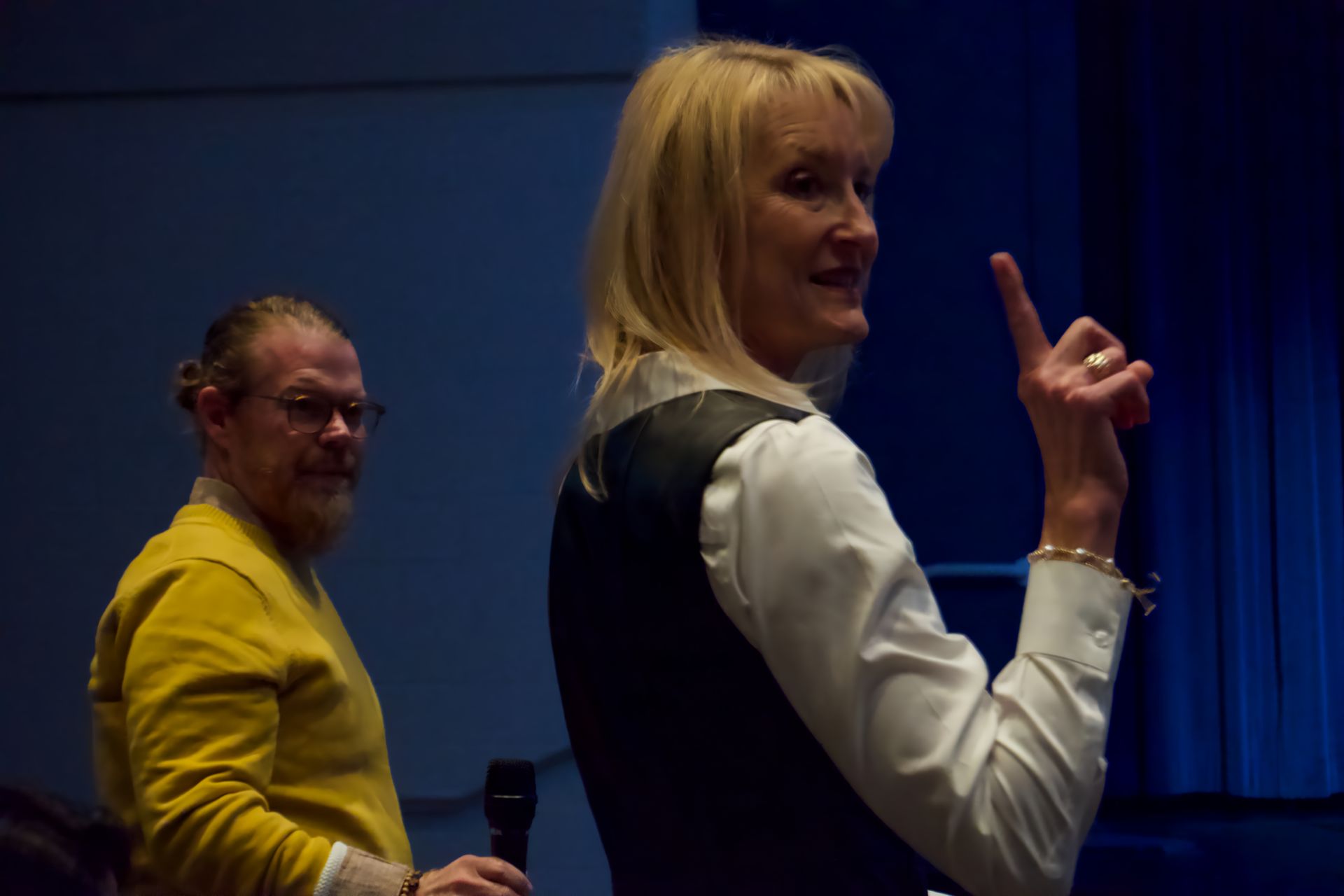 A man and a woman are standing in a dark room and the woman is pointing up