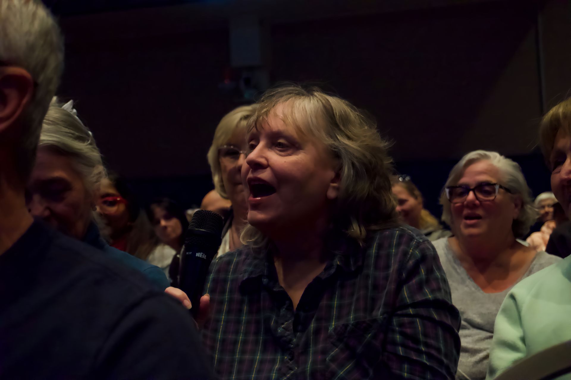 A woman is holding a microphone in a crowd of people.