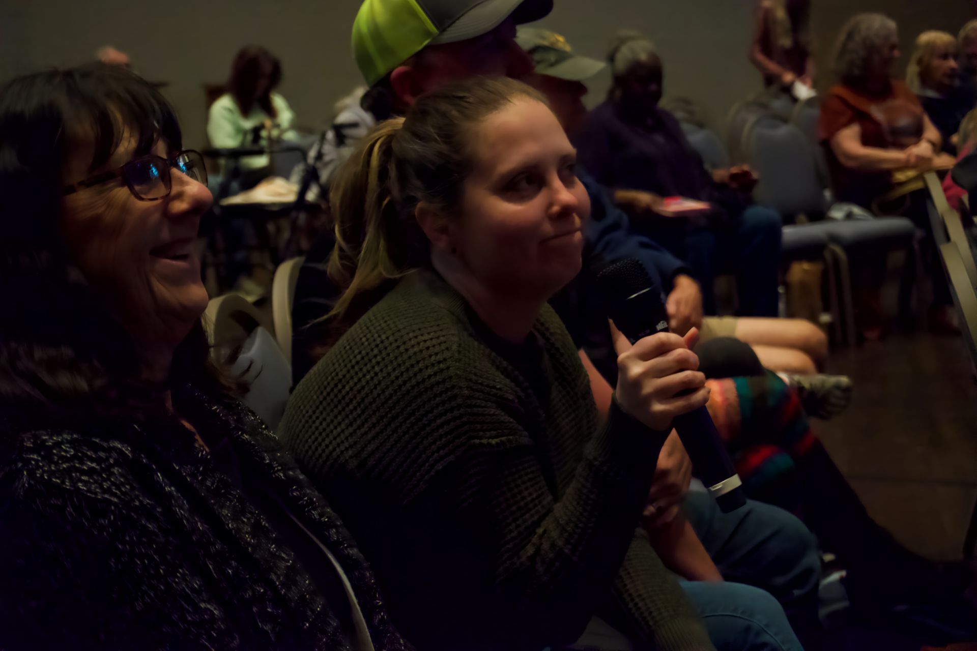 A group of people are sitting in chairs in a dark room.