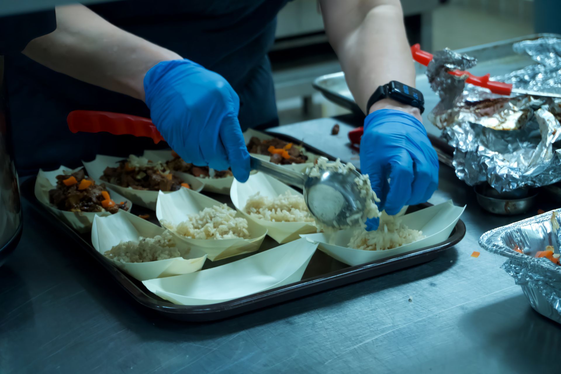 A person wearing blue gloves is preparing food on a table.