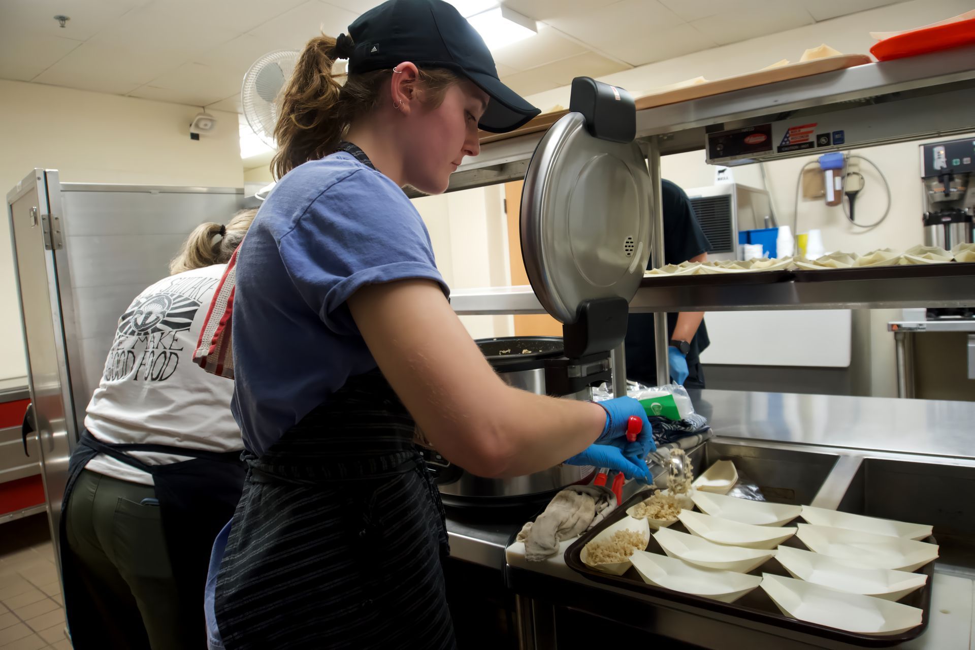 A woman is standing in a kitchen preparing food.