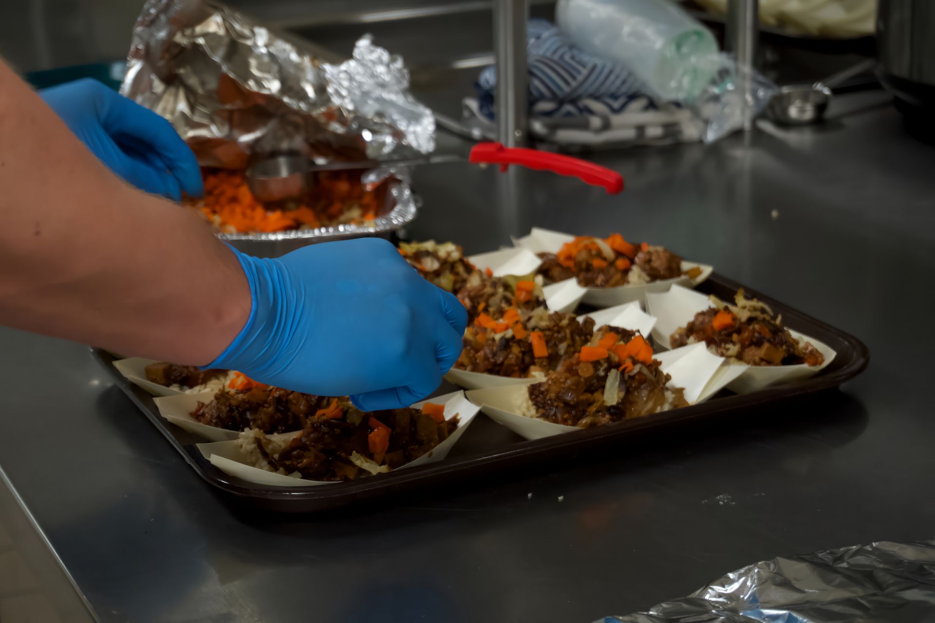 A person wearing blue gloves is preparing food on a tray.