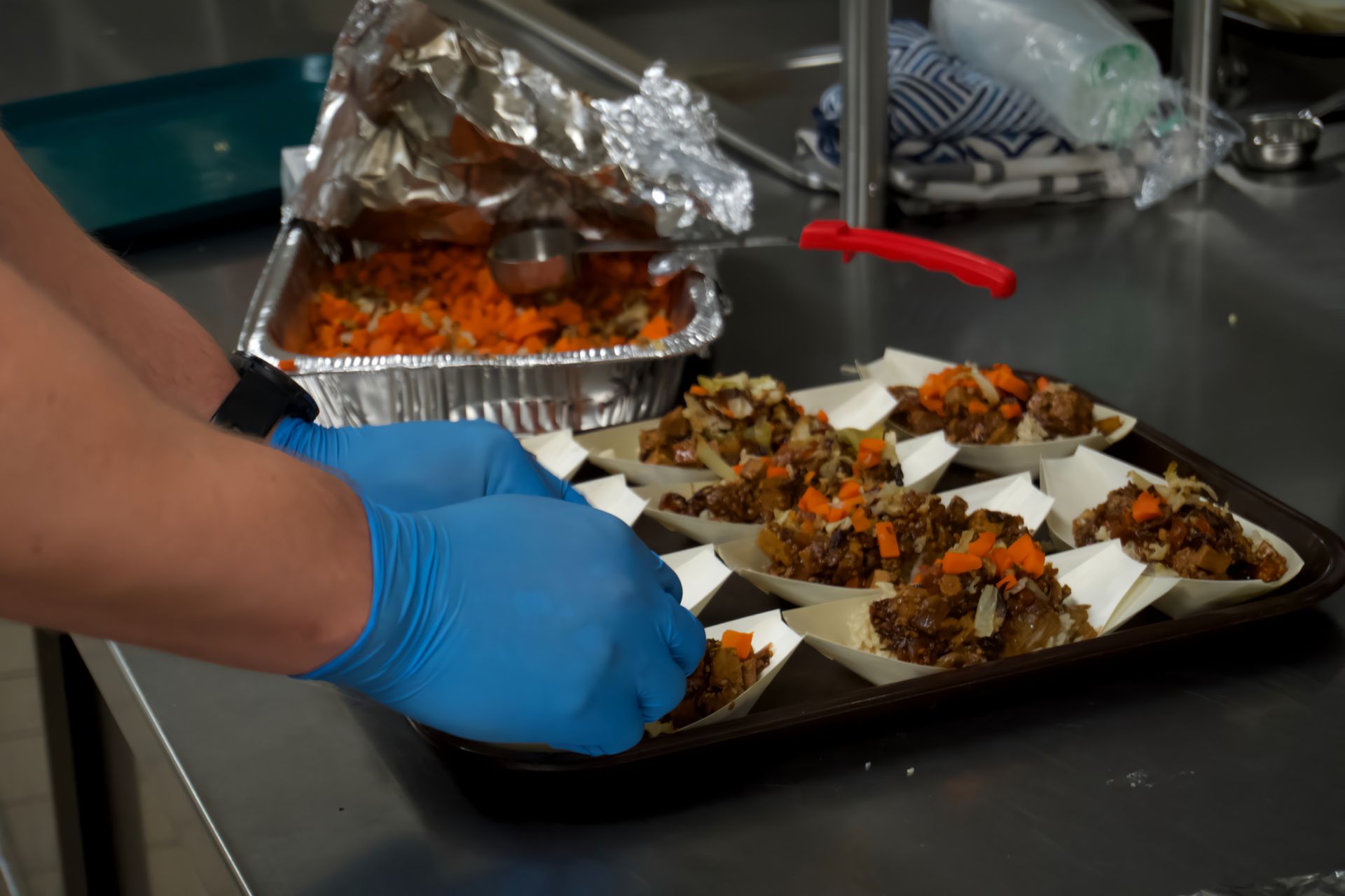 A person wearing blue gloves is preparing food on a tray.