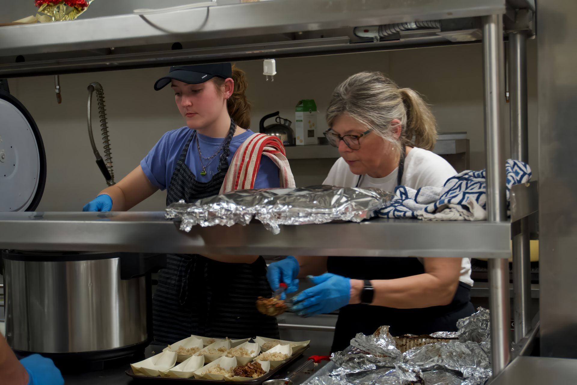 Two women are preparing food in a kitchen.