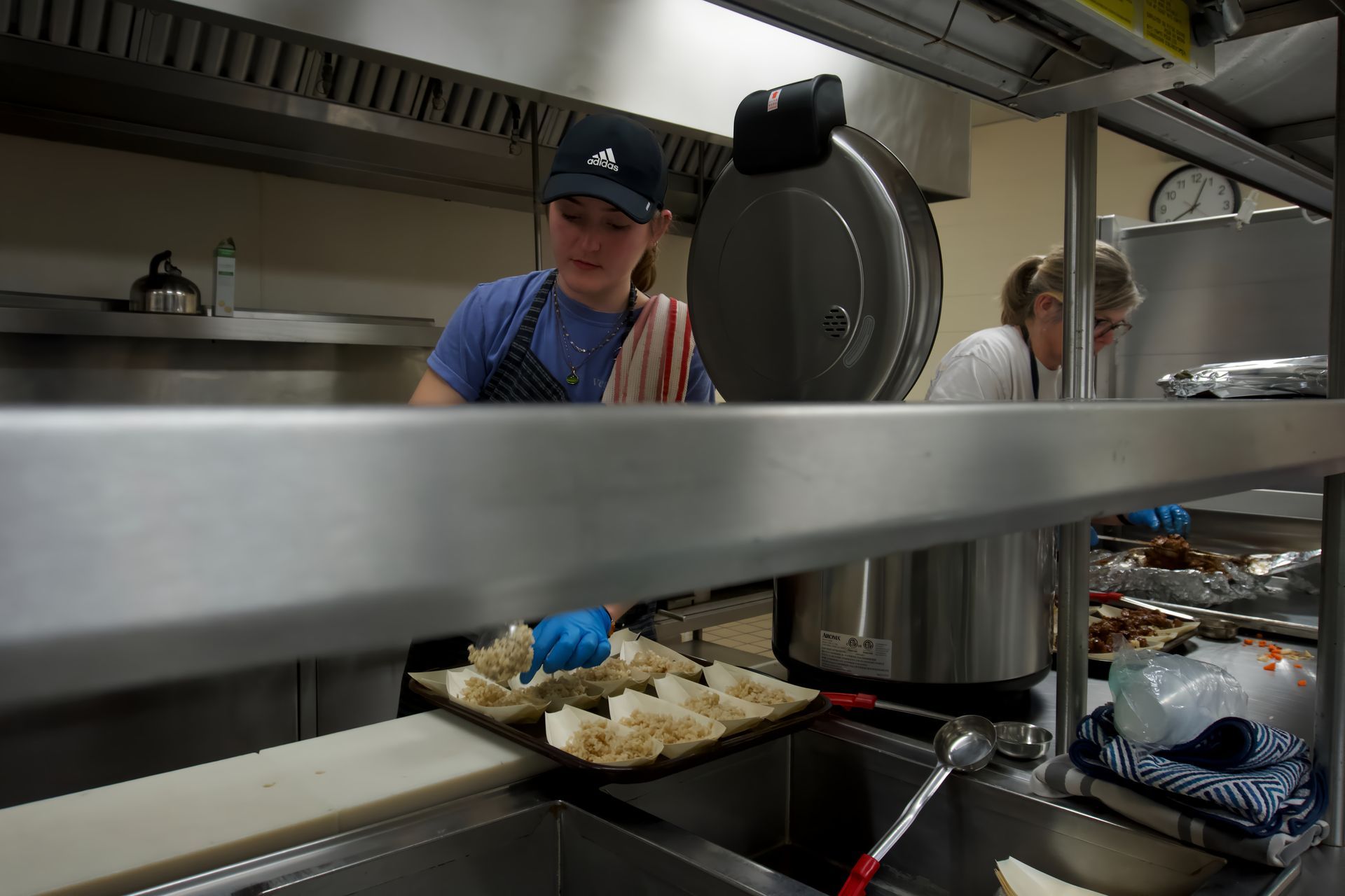 A woman in a blue hat is working in a kitchen