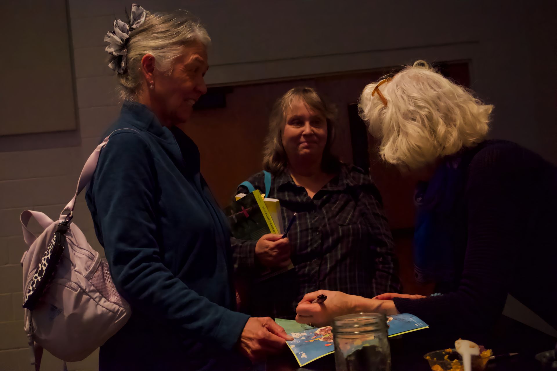 A group of women are standing around a table talking to each other.