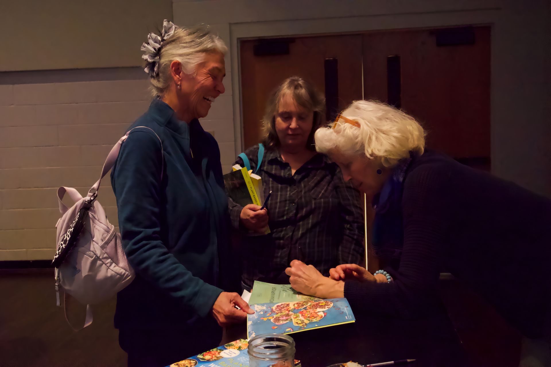 Three women are standing around a table looking at a piece of paper
