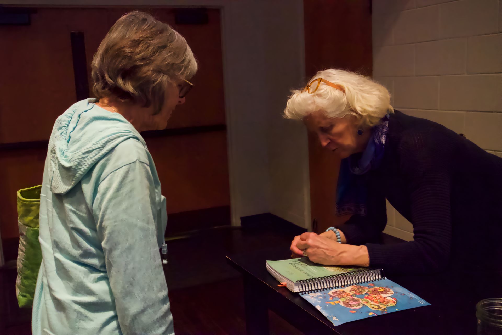 A woman is signing a book for another woman.