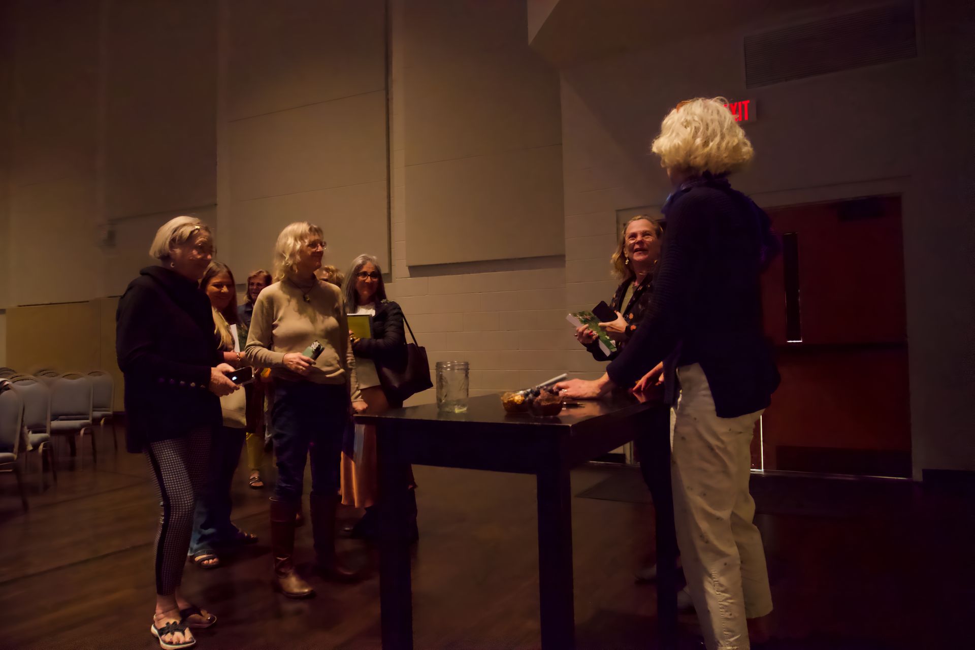 A group of women are standing around a table in a dark room.