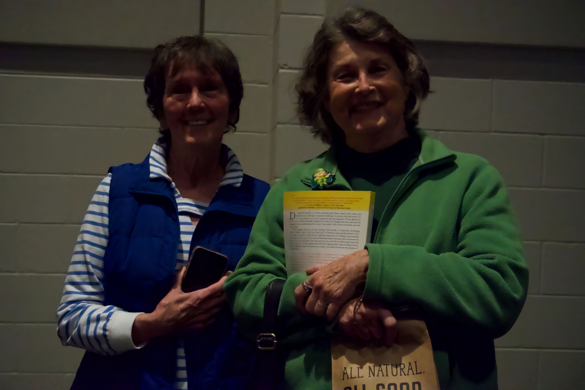 Two women are standing next to each other and one is holding a bag that says all natural all good
