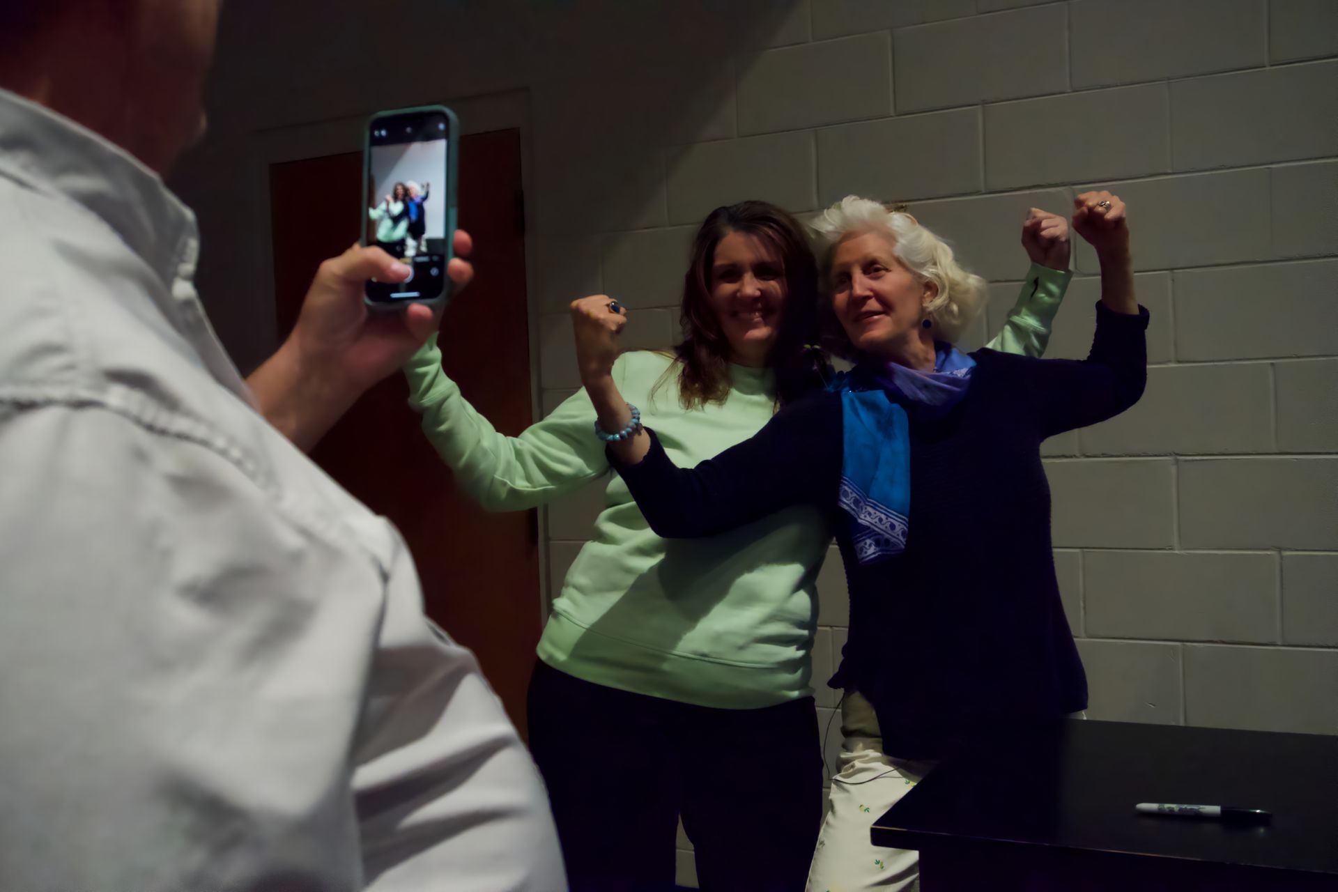 A man is taking a picture of two women with their arms in the air