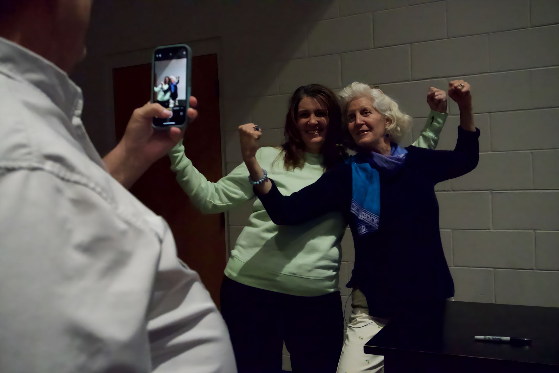 A man is taking a picture of two women with their arms in the air