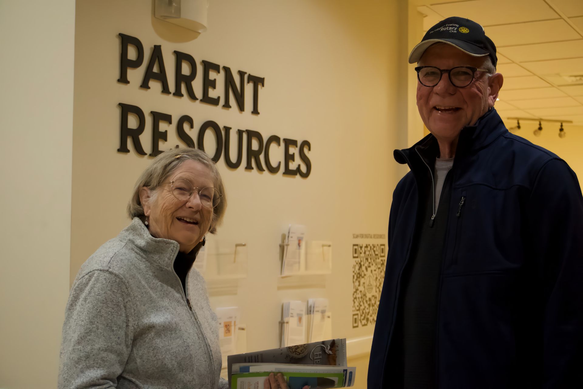A man and a woman are standing in front of a sign that says parent resources.