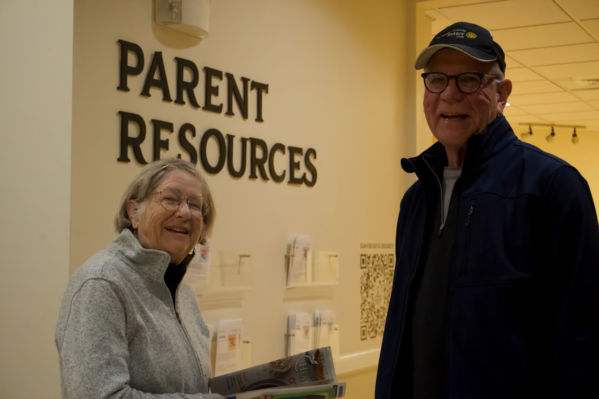 A man and a woman are standing in front of a sign that says parent resources.