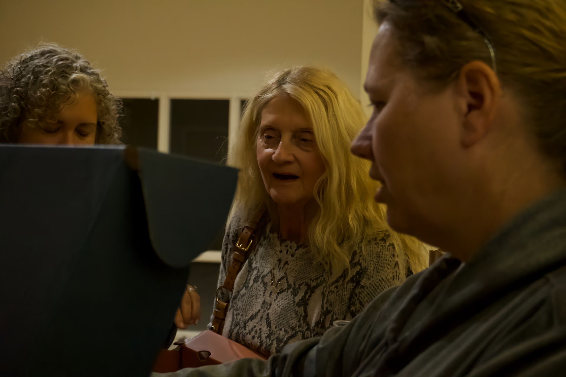 Three women are sitting around a table looking at a laptop computer.