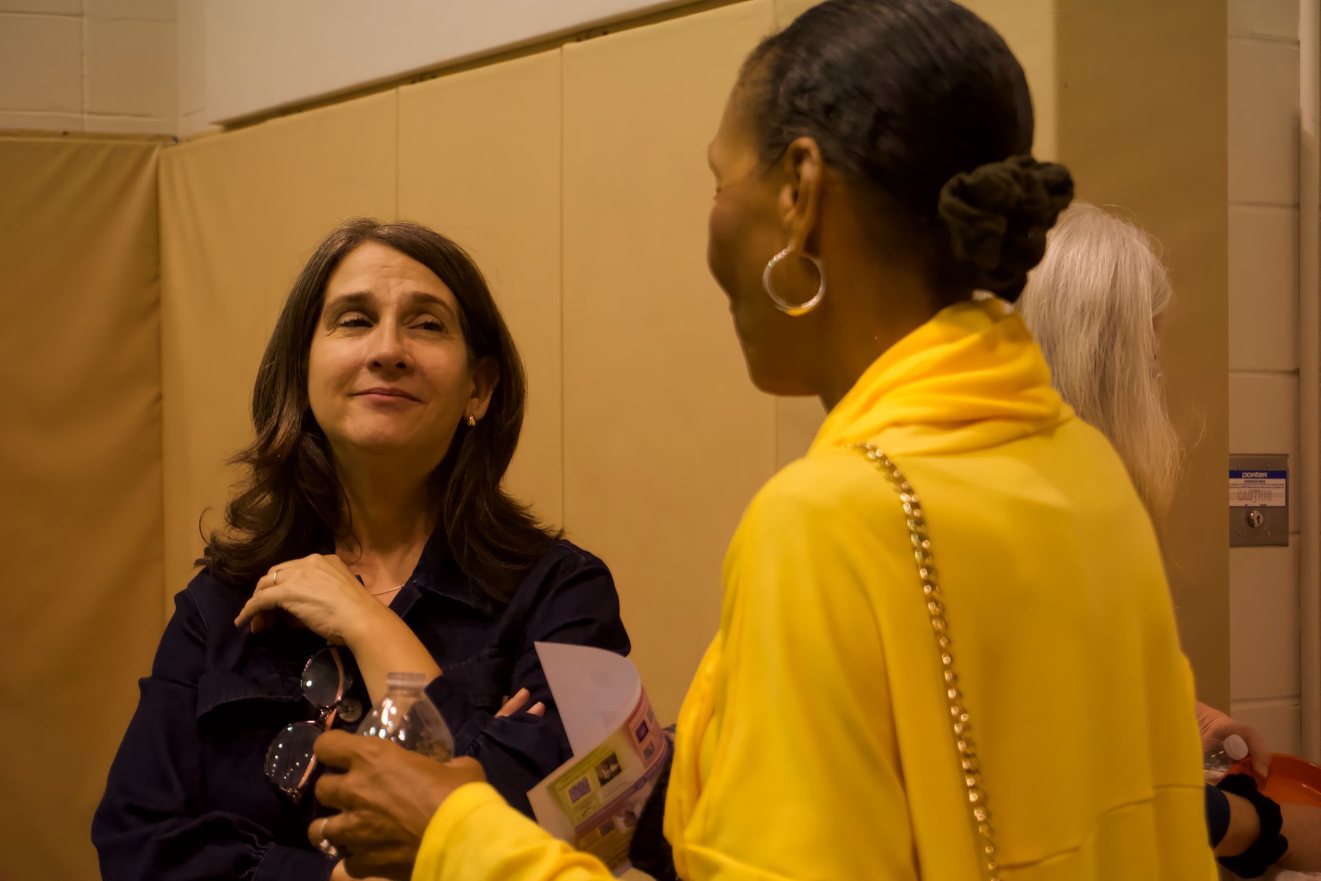 A woman in a yellow shirt is talking to another woman