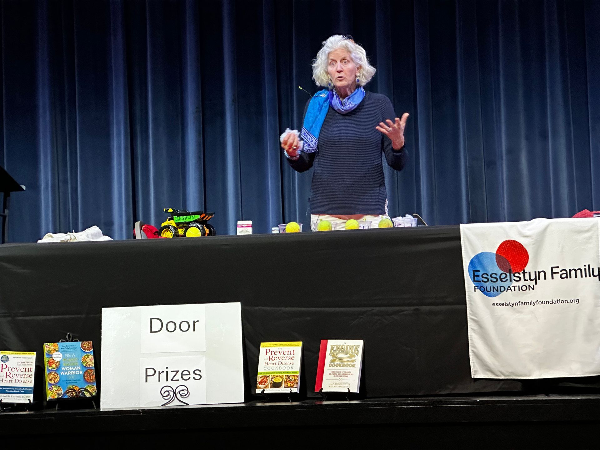 A woman stands behind a table with a sign that says door prizes