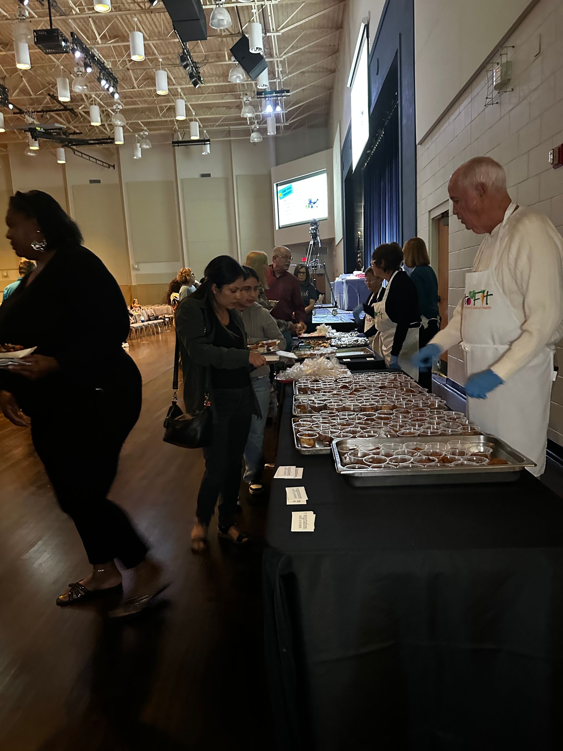 A group of people are standing around a table with trays of food.