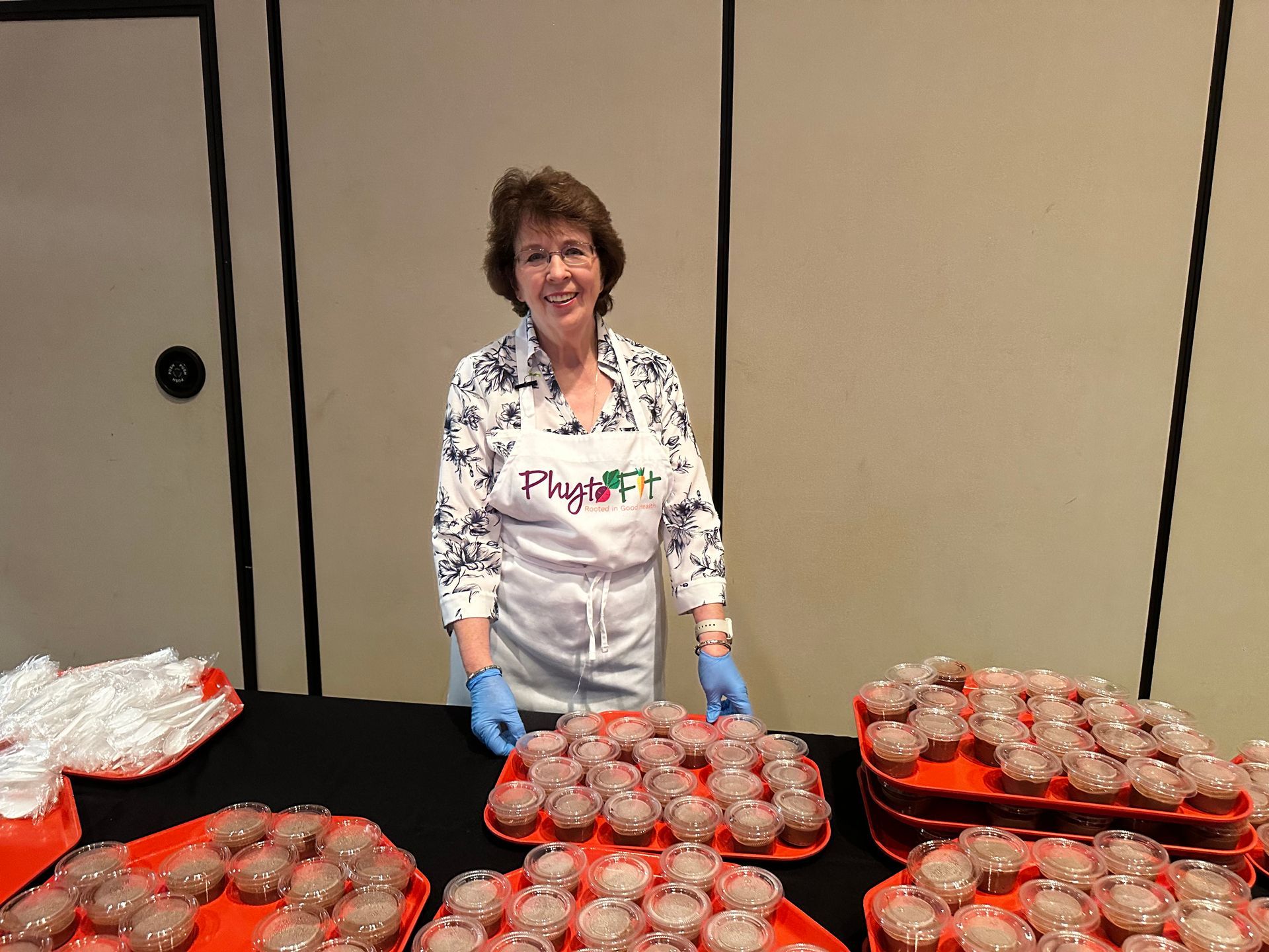 A woman is standing in front of a table full of cupcakes.