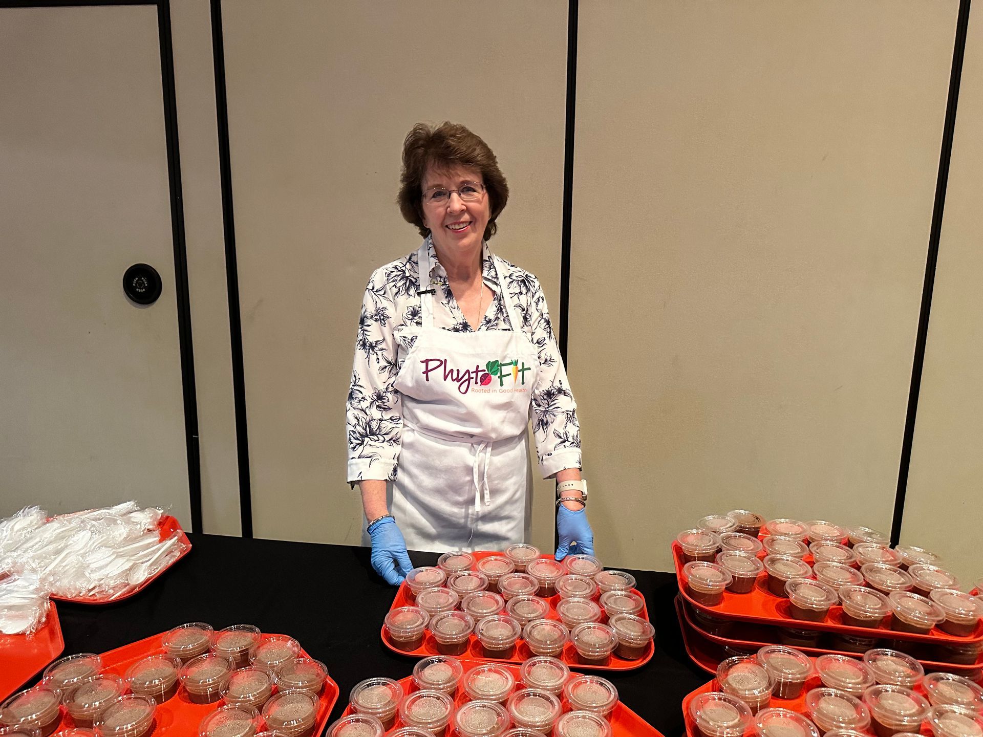 A woman is standing in front of a table full of cupcakes.