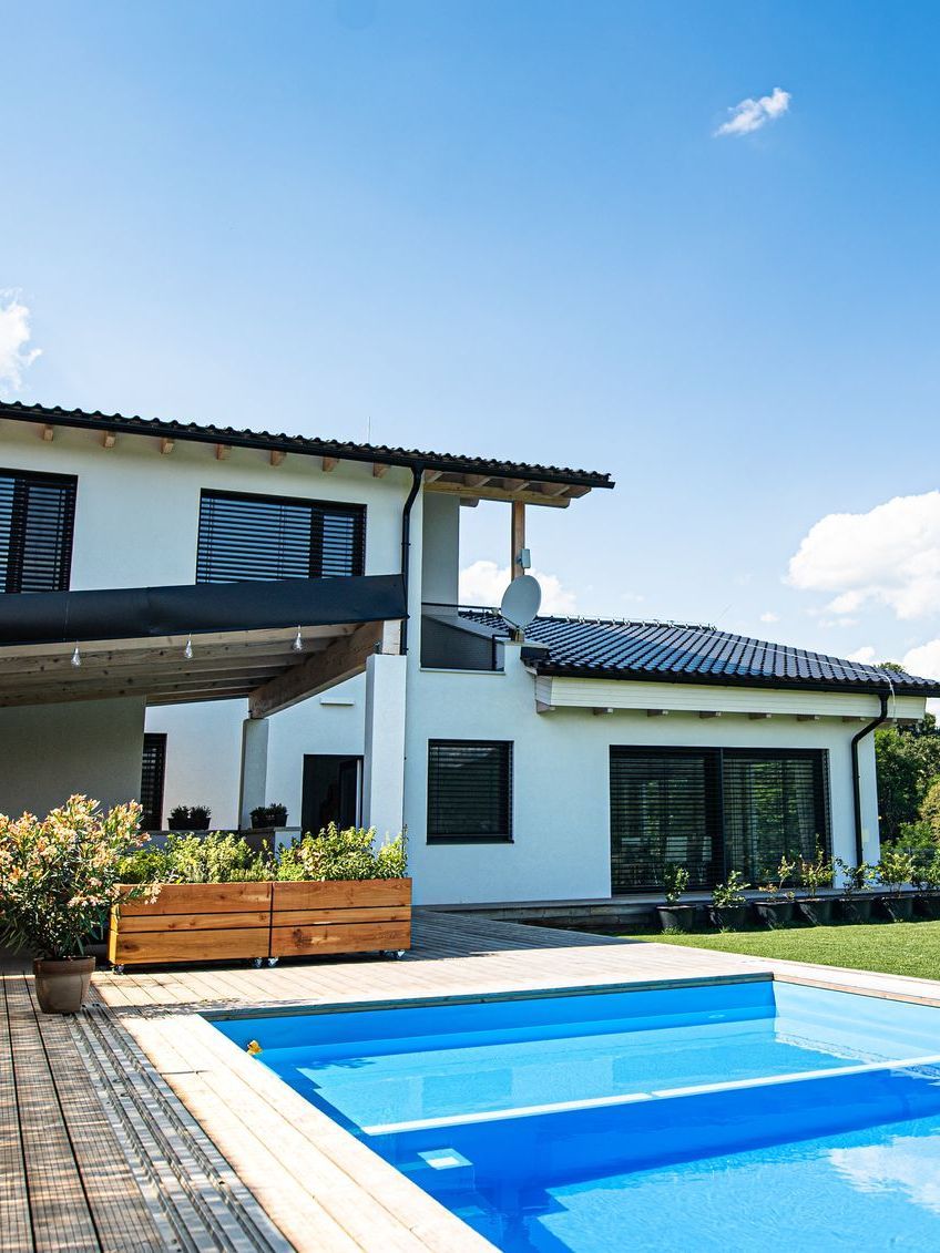 A white house with a large swimming pool in front of it