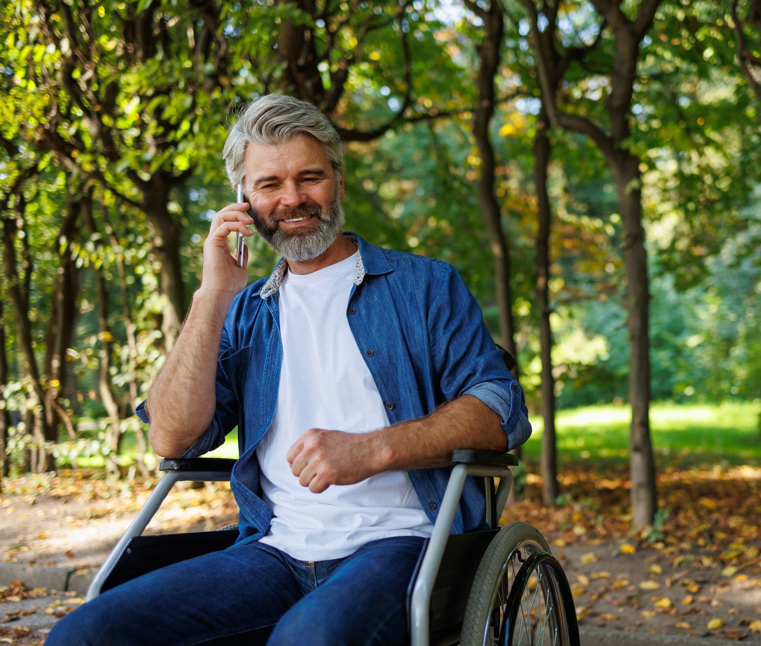 A man in a wheelchair is talking on a cell phone.