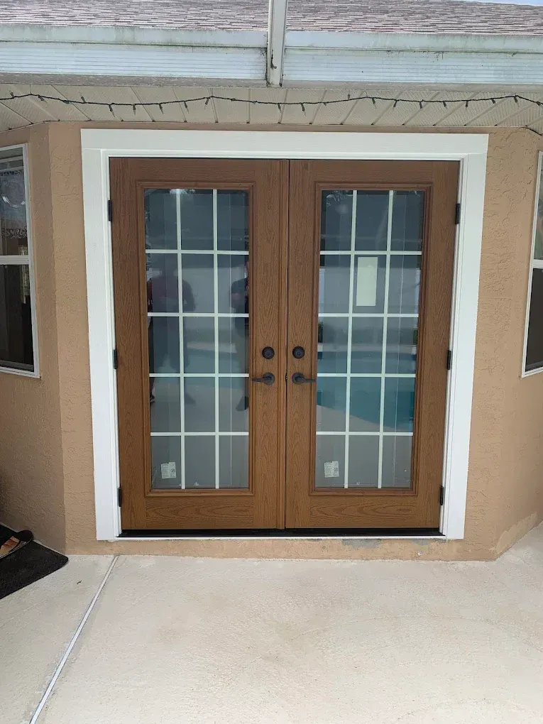 Wooden double front doors with glass panes and white trim at a house entrance