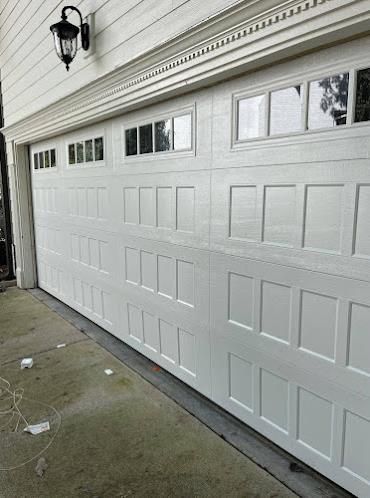 A white garage door with a lot of windows on a house.