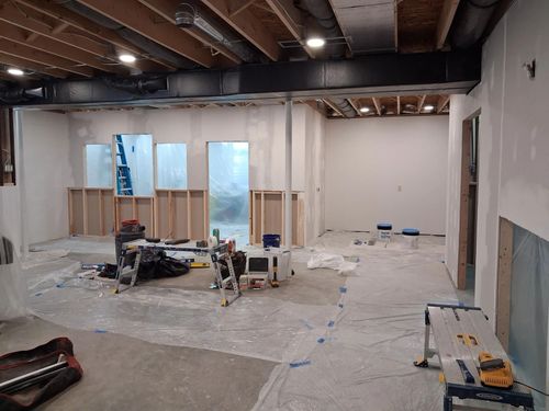 Interior under construction with exposed beams, framed walls, tools, and materials on the floor.