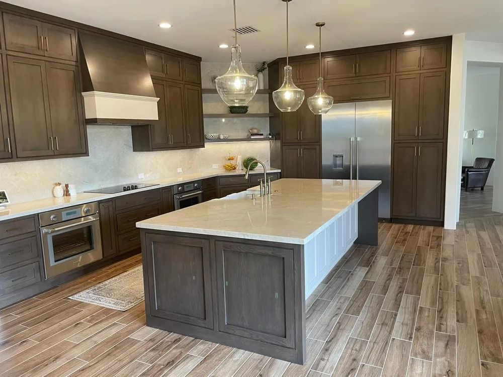 Modern kitchen with dark wood cabinets, large island, stainless appliances, and pendant lights
