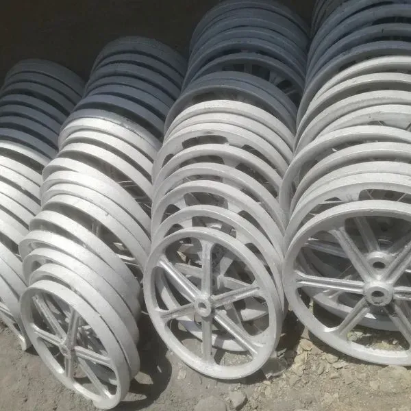 Montones de ruedas de metal de color plateado con radios, posiblemente para maquinaria, dispuestas al aire libre.