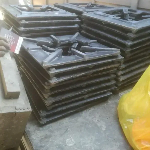 Pilas de rejillas de quemadores de gas de hierro fundido negro en un entorno de taller.