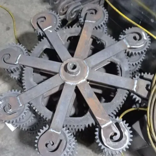 Conjunto de engranajes metálicos con brazos radiales y remolinos decorativos.
