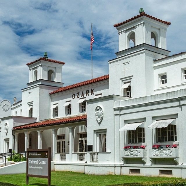White Ozark Cultural Center building with two towers, American flag, and a sign in front.