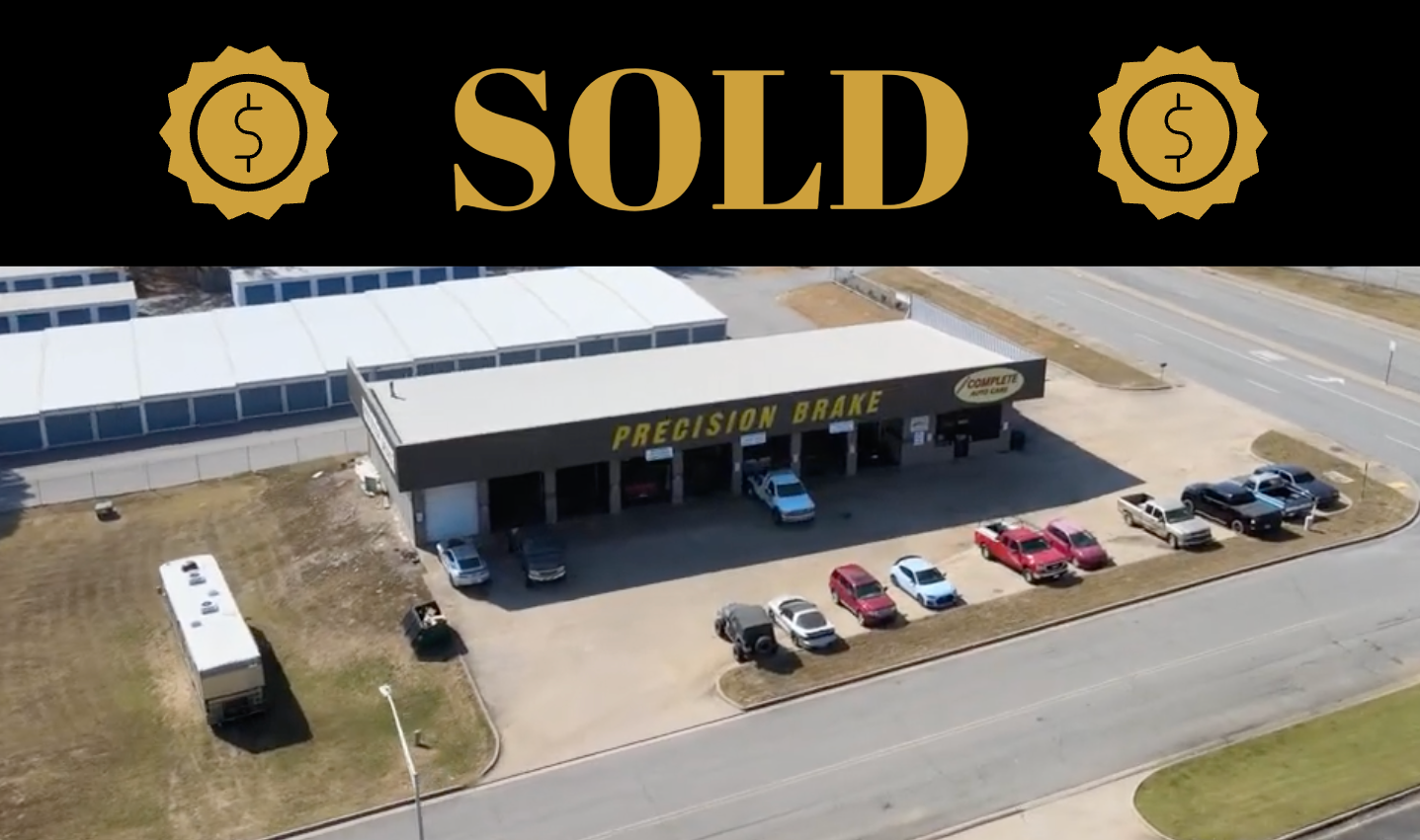 Aerial view of Precision Tune auto shop with cars parked outside, storage units and a road visible.