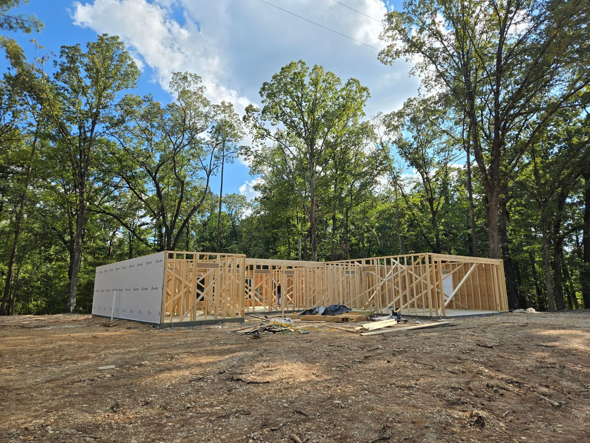 Yellow two-story house with blue door and windows. Bare trees and brown yard under a blue sky.