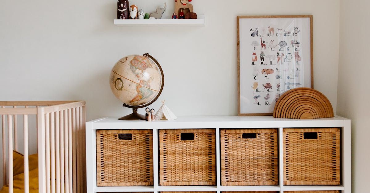 A nursery with a crib, storage unit with baskets, globe, and framed art.