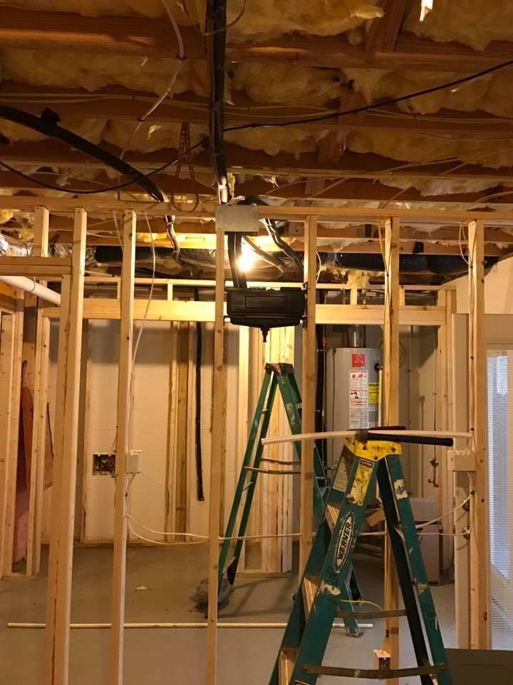 Framed basement walls under construction with exposed wooden beams, insulation, and ladders in the center.