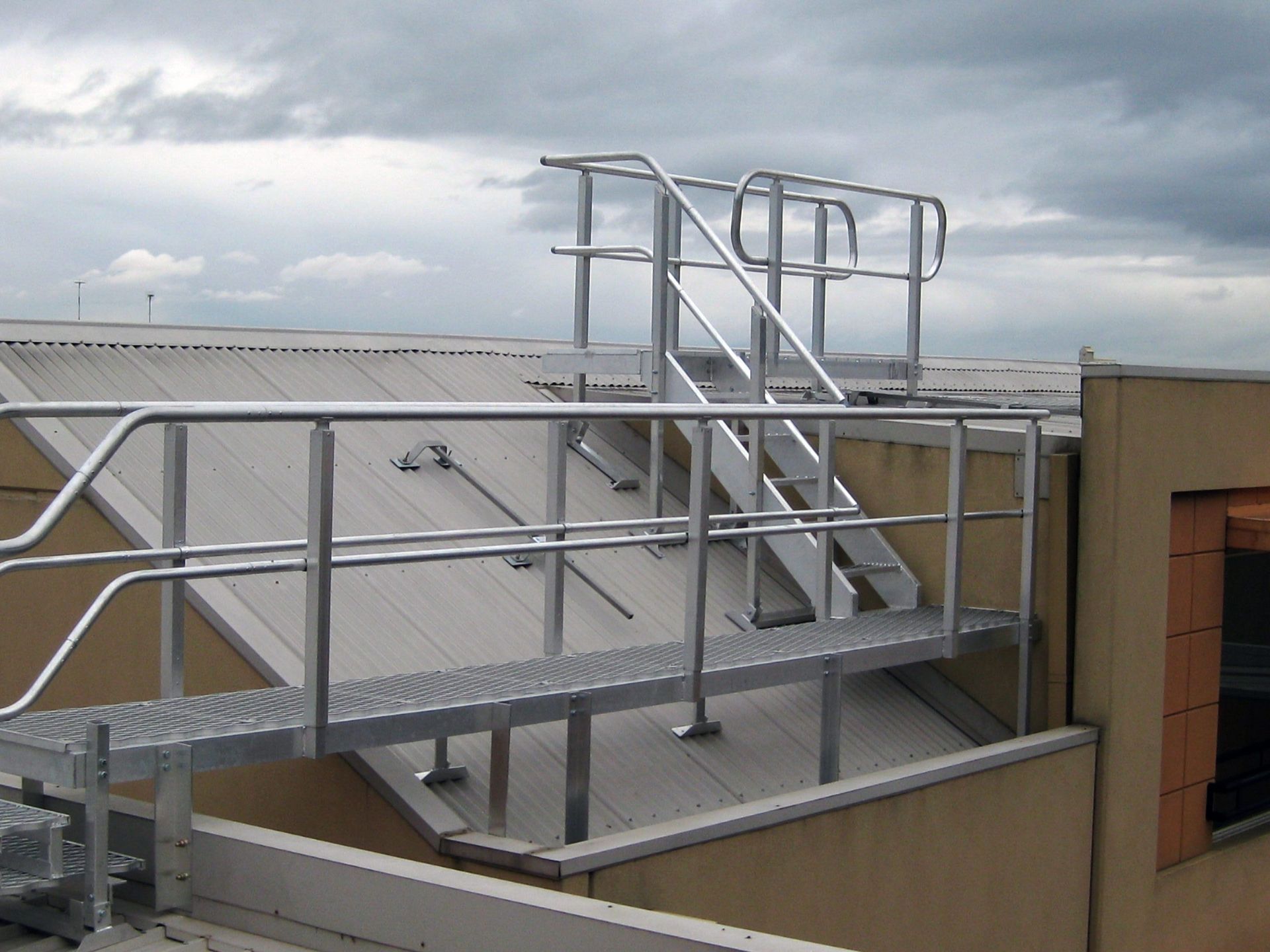 Metal walkway and stairs on a building roof, providing access to a higher level.